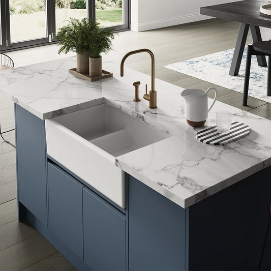 Modern kitchen with blue island, marble countertop, and white fireclay sink.